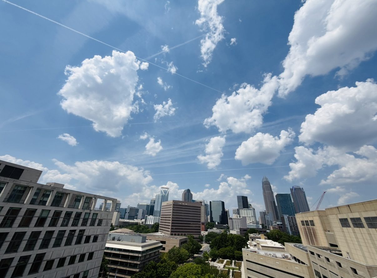 Wide view of the Charlotte skyline beneath tall summer clouds