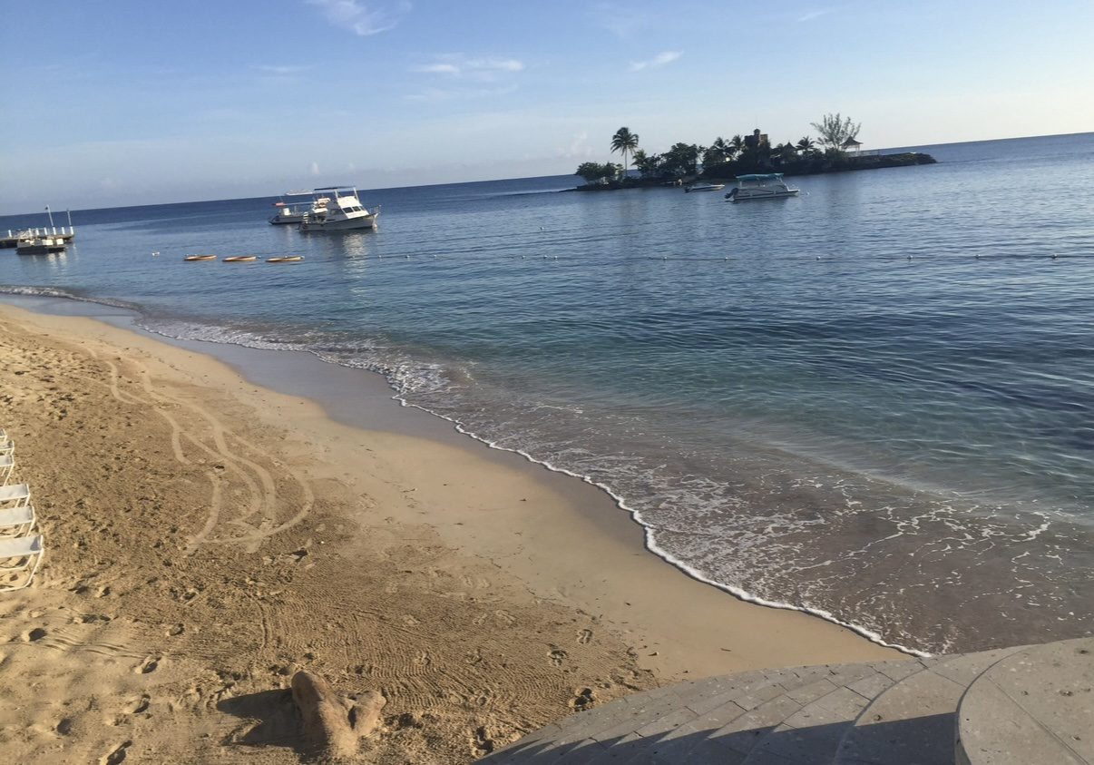 Boats moored off a calm sand beach in the early morning