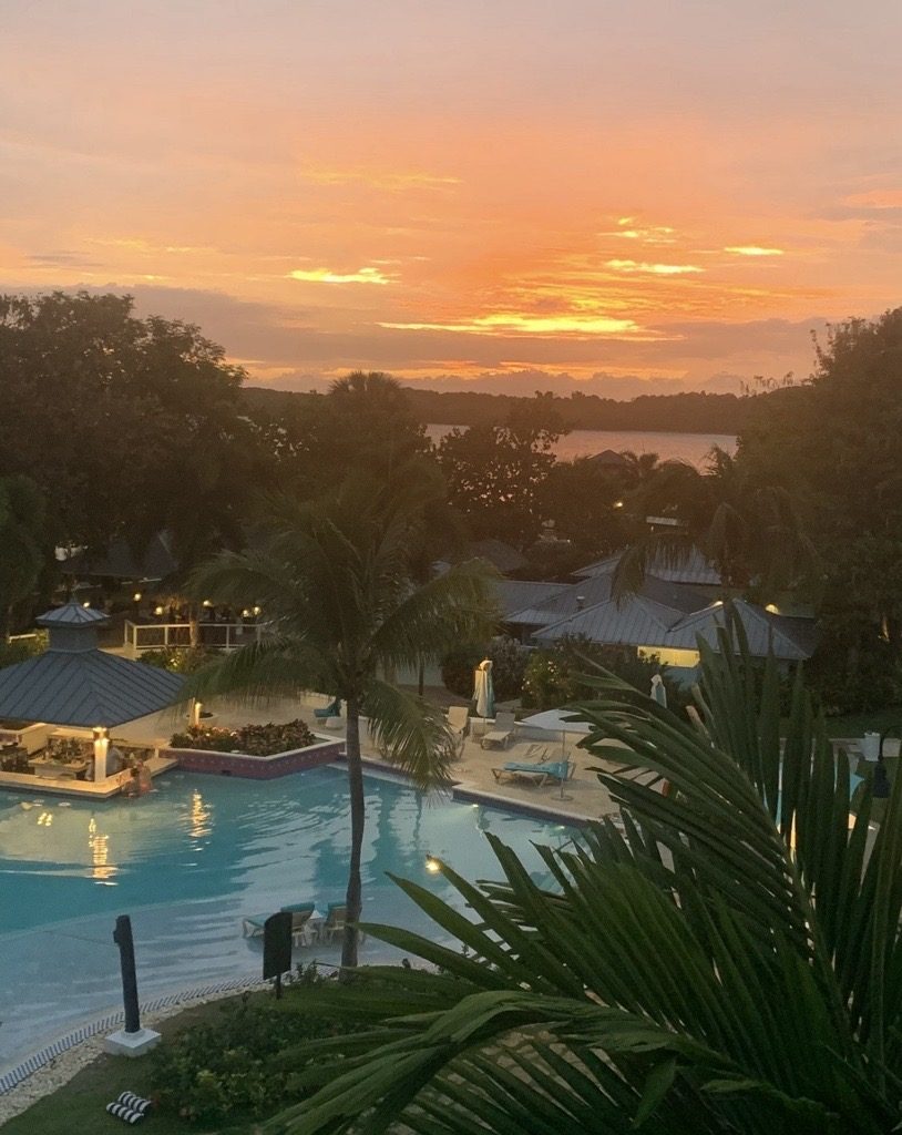 Orange sunset burning over a palm-lined resort pool